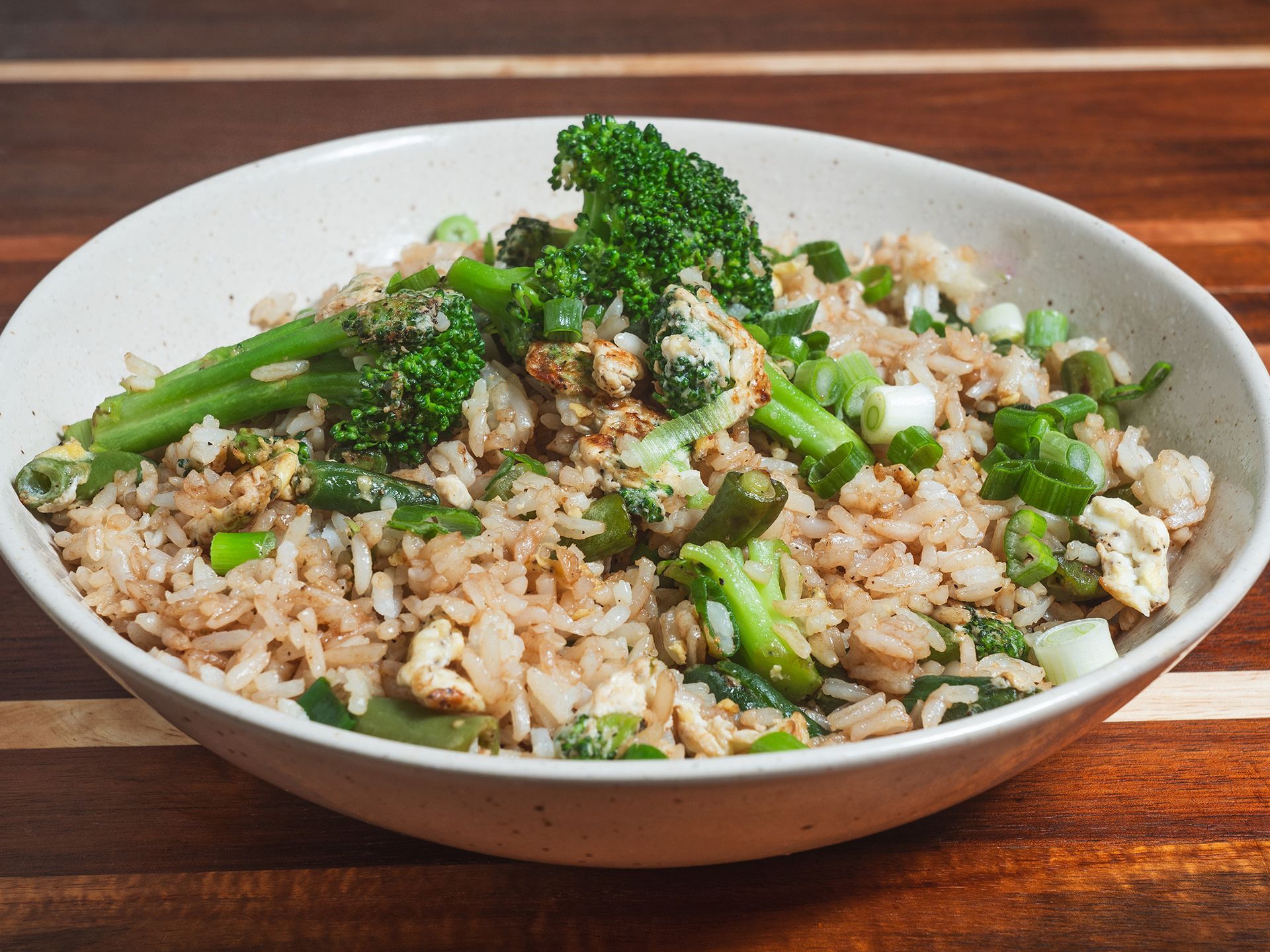 Bowl of vegetable fried rice with broccoli, green onions, and eggs.