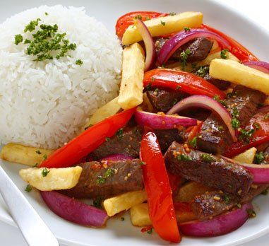 Lomo saltado with rice: beef stir-fry with fries, red onion, and peppers next to a scoop of white rice.