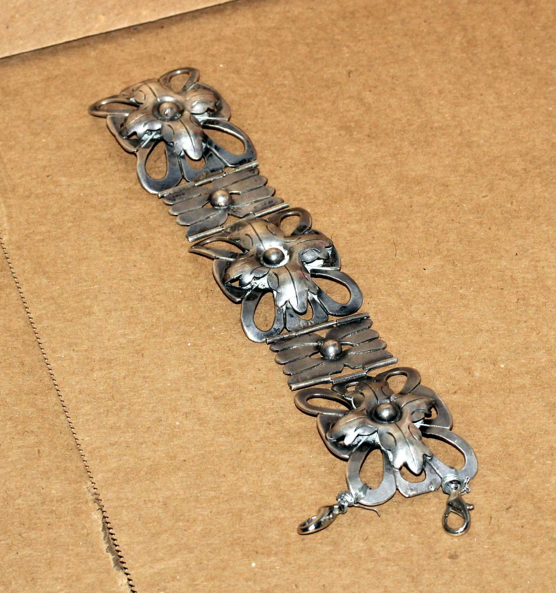 Silver bracelet with floral designs and textured links.