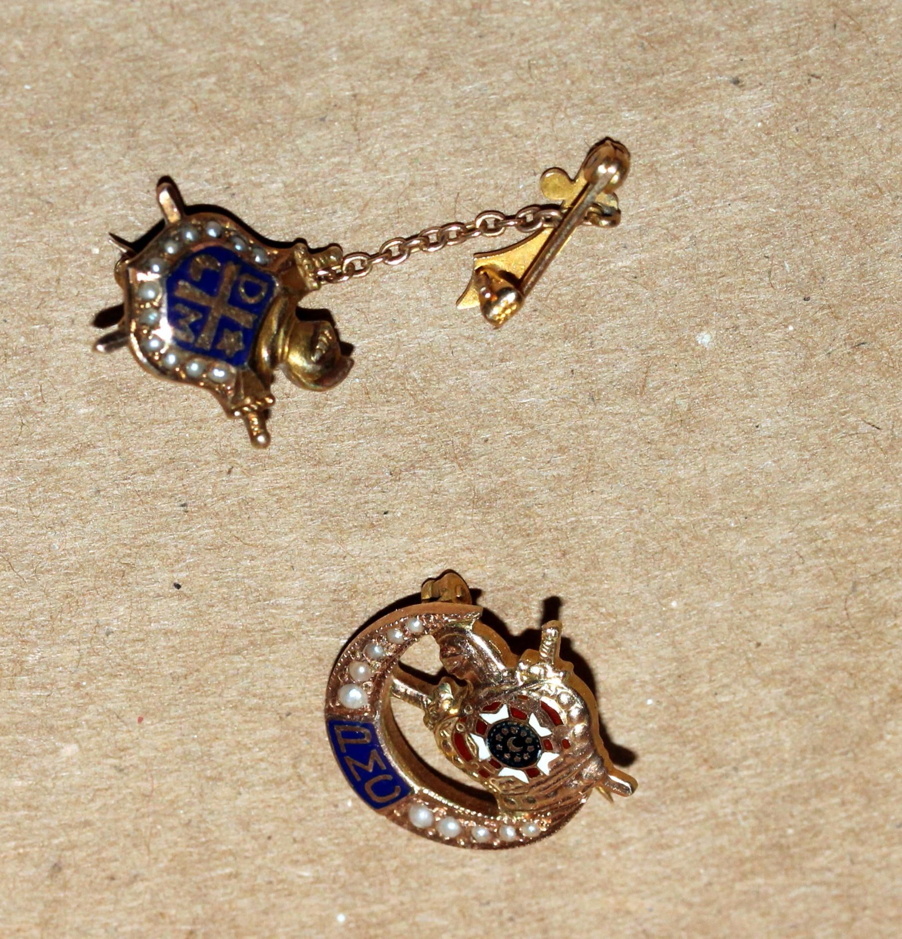 Two antique gold and blue pins, one nautical-themed, the other with a soccer ball.