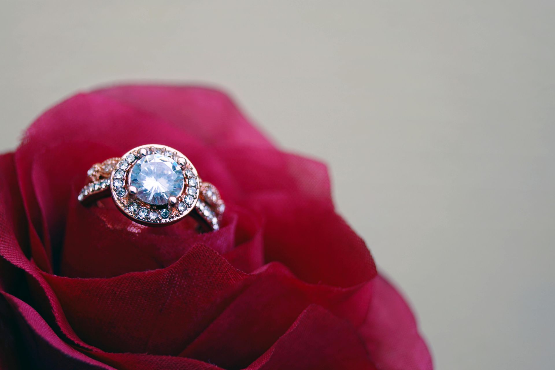 Rose gold ring with a light blue center stone on a red rose.