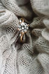 Diamond engagement ring nestled in gray fabric.
