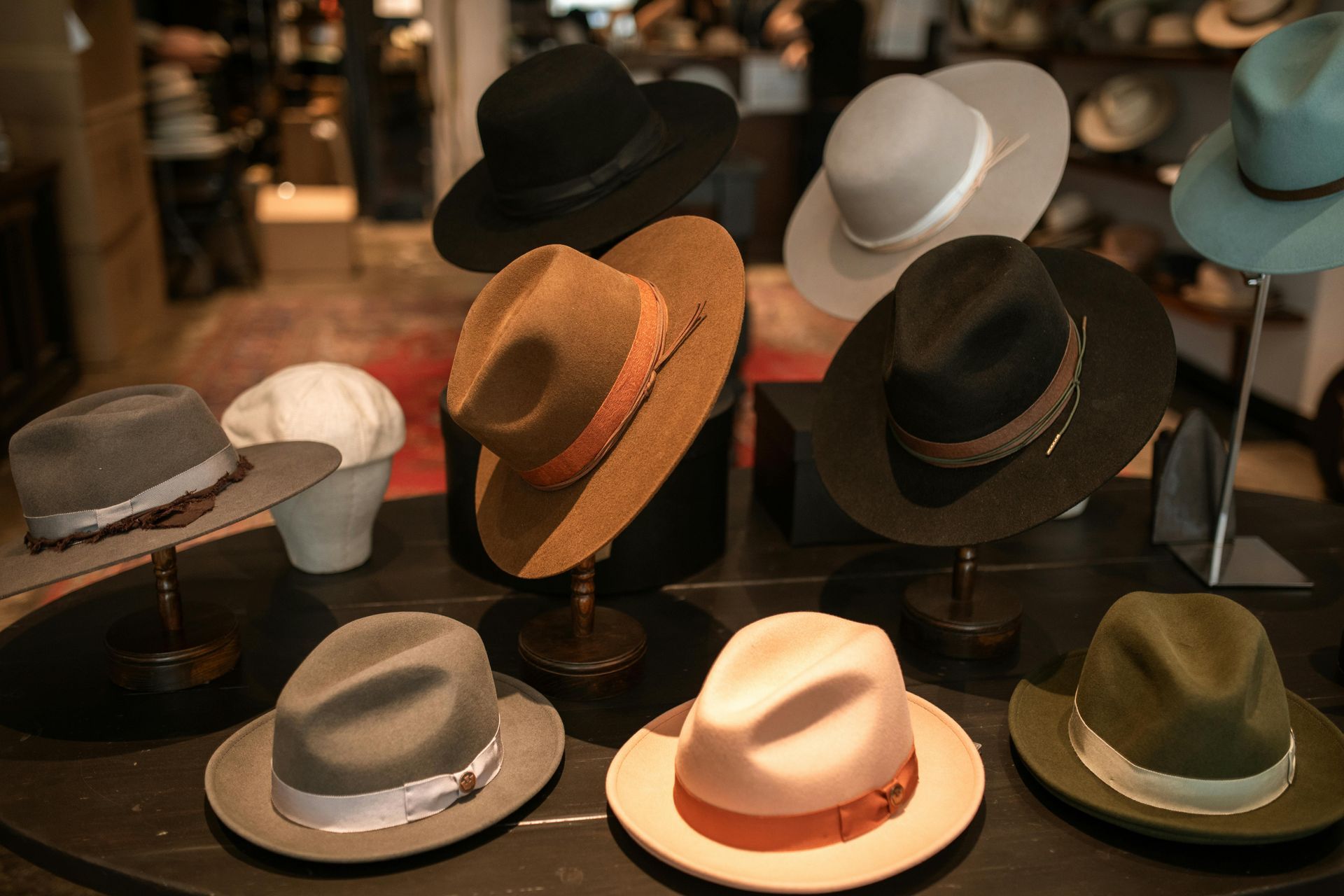 Display of various fedora hats on pedestals, in a shop.