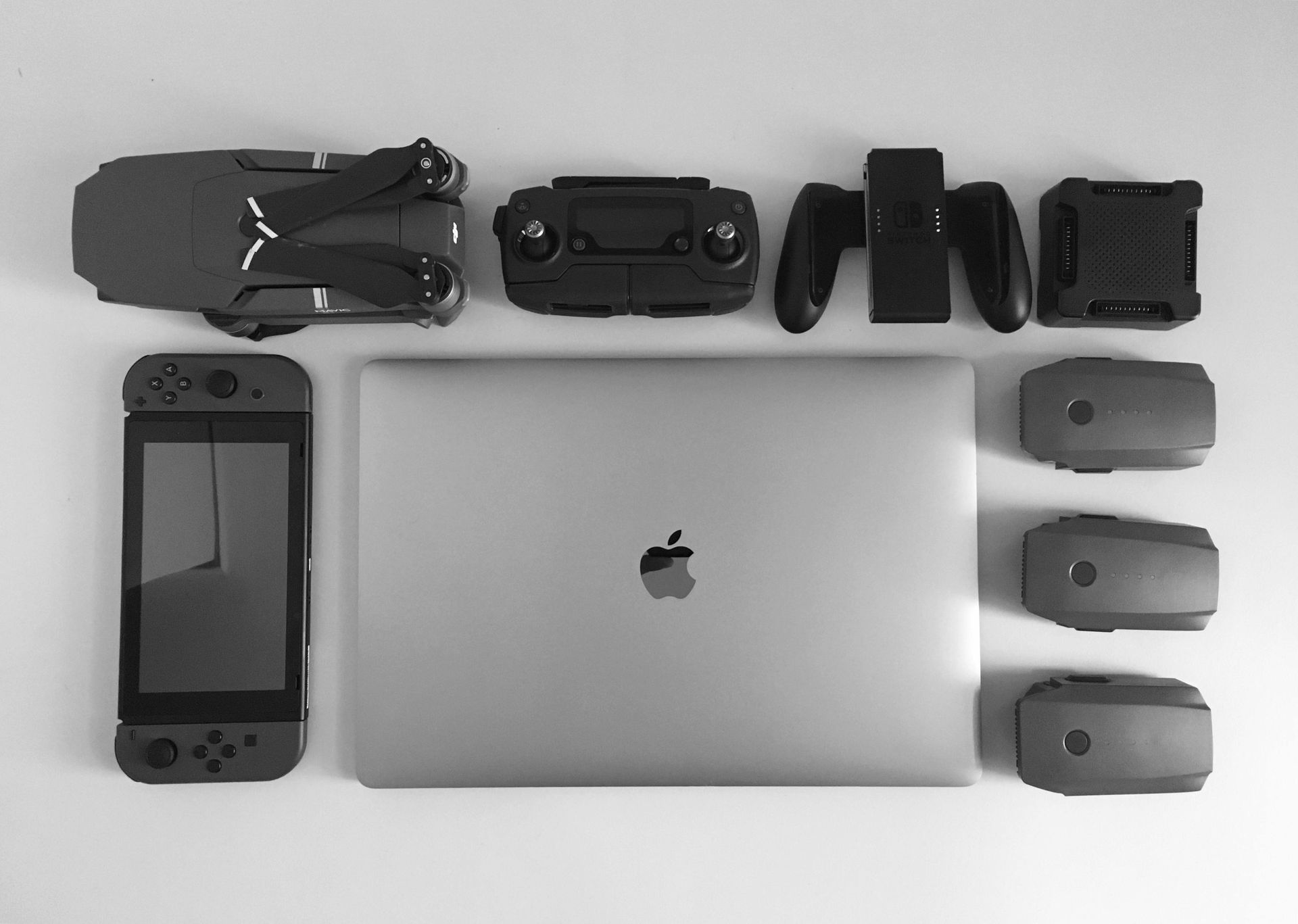Collection of tech devices: drone, controller, game controllers, laptop, VR headsets, and a handheld game console.