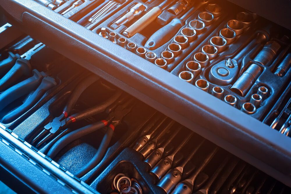Toolbox drawer open, filled with various hand tools: sockets, wrenches, pliers, and screwdrivers.