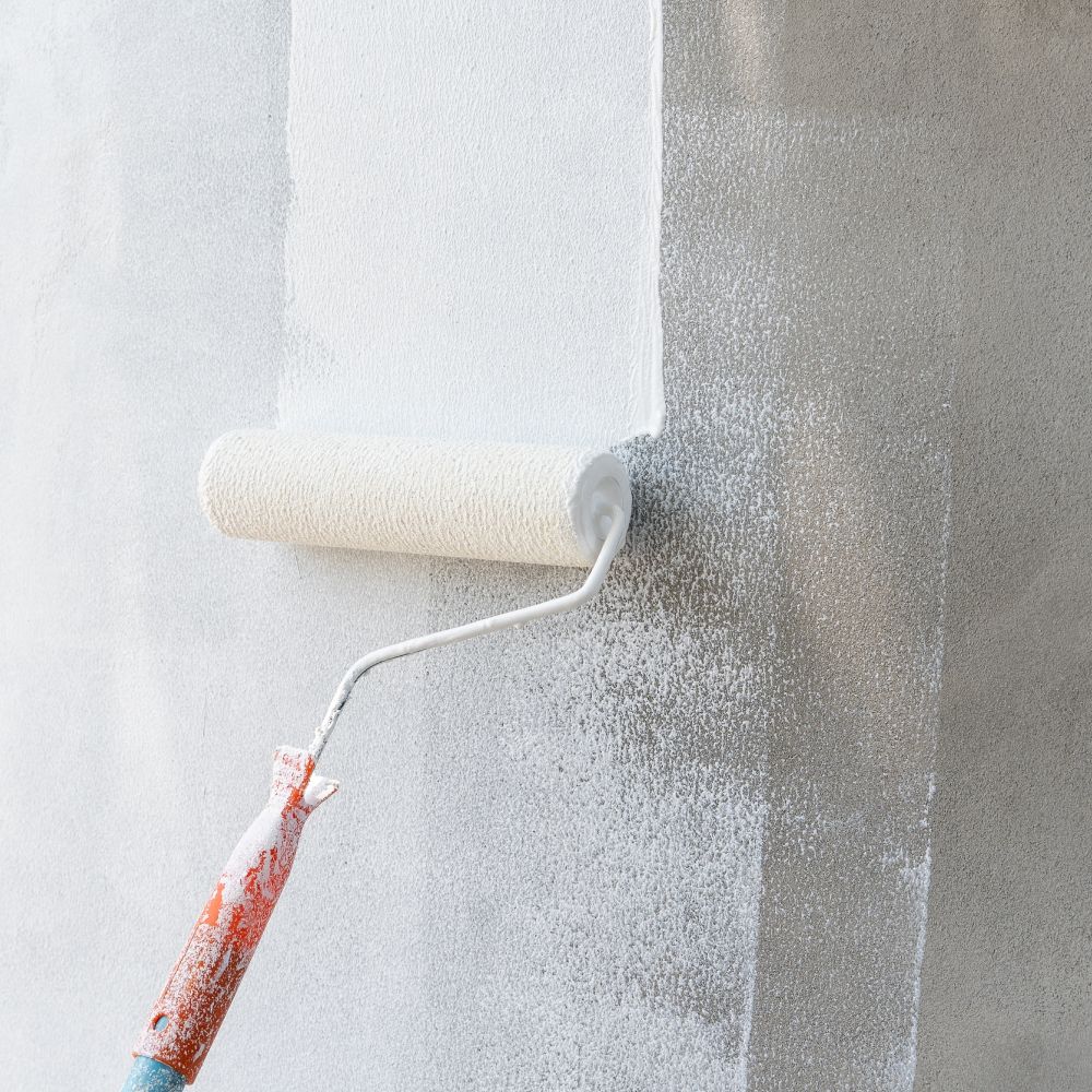 A person is painting a wall with a paint roller.