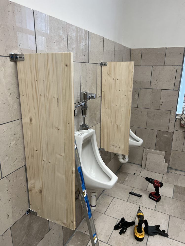 A bathroom with two urinals and a wooden divider.