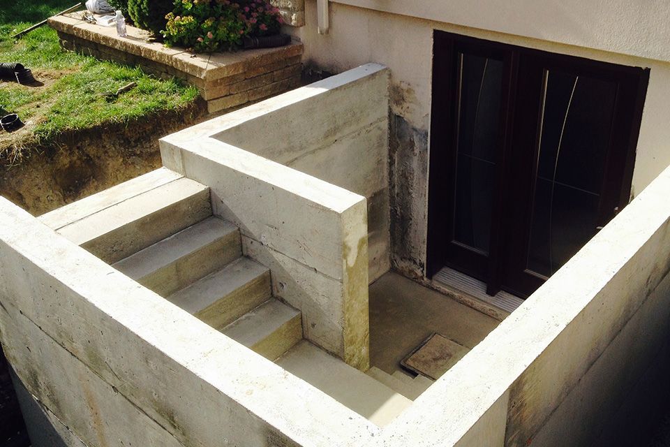 Un mur en béton avec des escaliers menant à une porte de sous-sol.