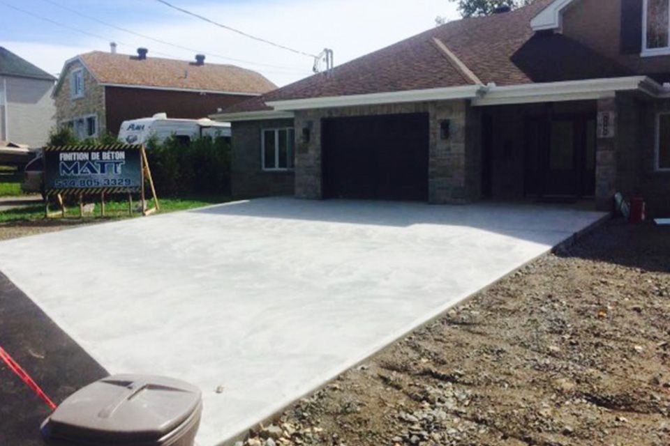 Une allée en béton est en cours de construction devant une maison.