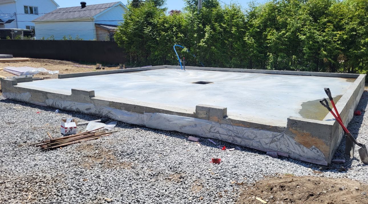 Une grande dalle de béton repose sur un terrain en gravier.