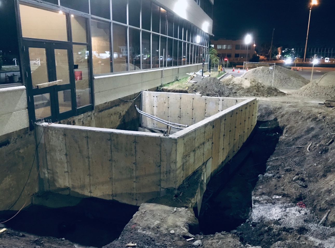 Un mur de béton est en train d'être construit devant un bâtiment la nuit.