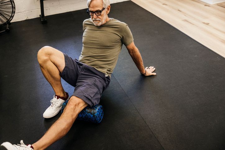 Woman on exercise ball assisted by a therapist in a gym setting.