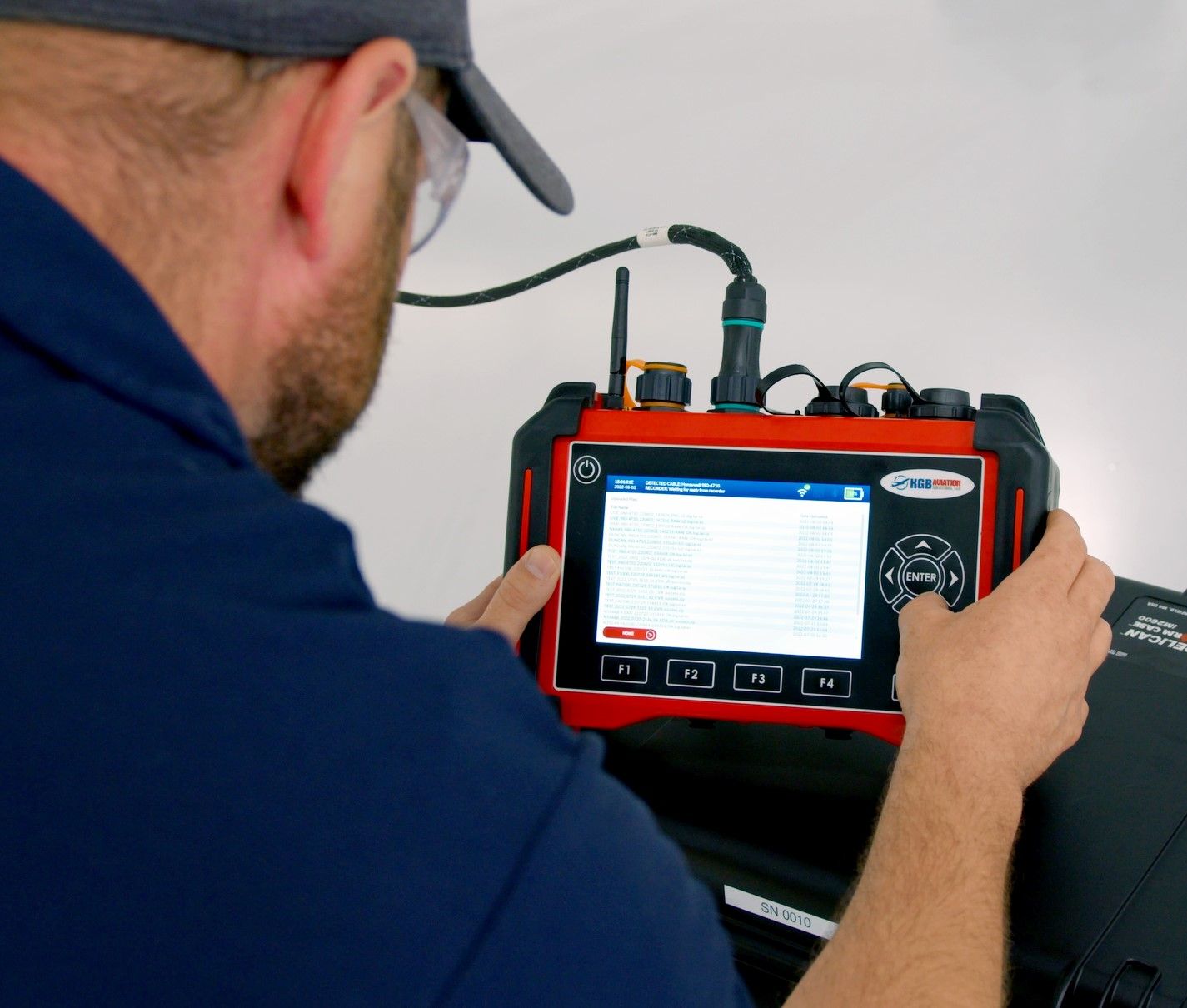 A man wearing a hat and glasses is using a red and black device