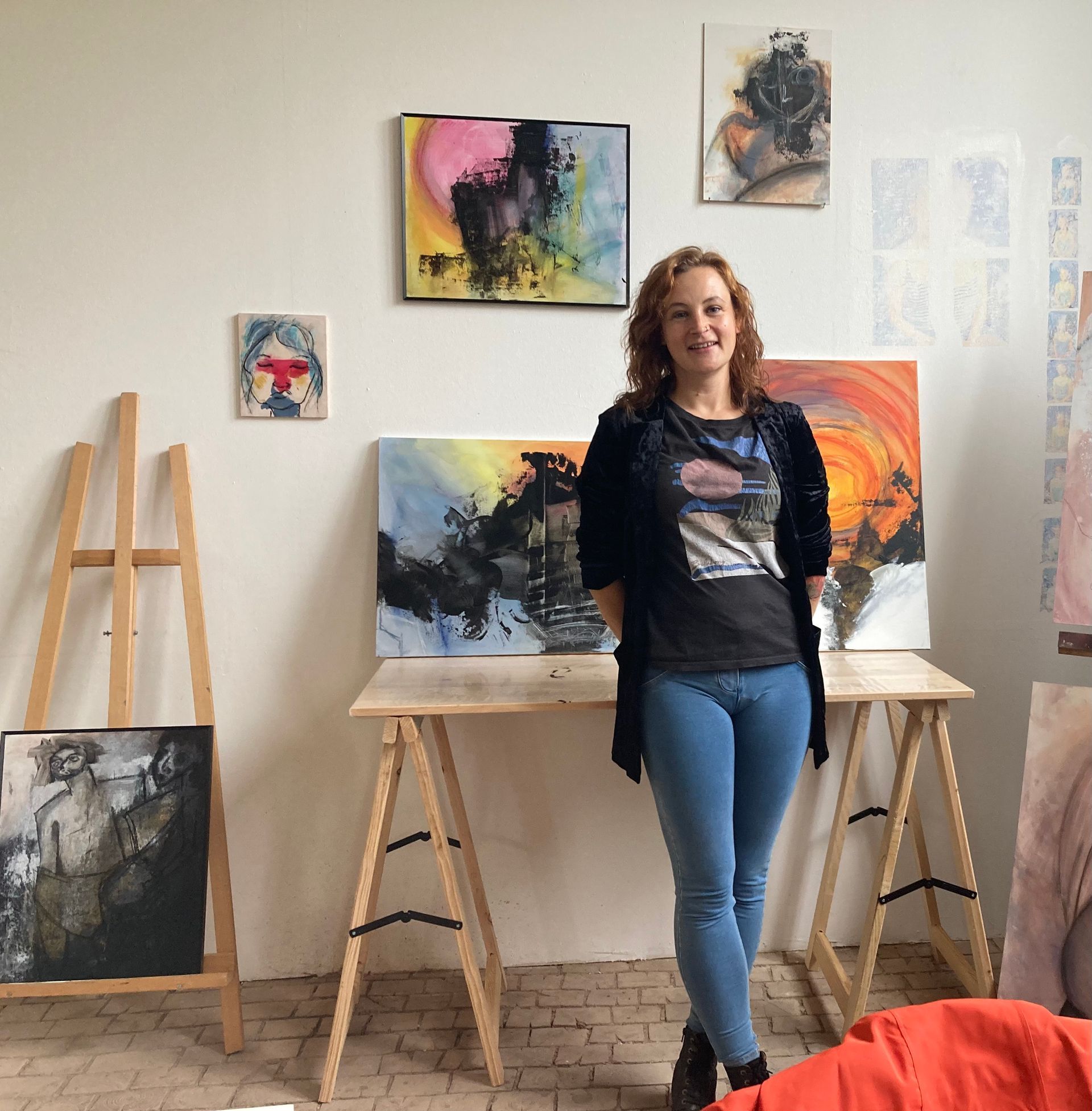 Das Foto zeigt die Malerin Sara-Lena Möllenkamp vor ihren Bildern in ihrem Atelier.