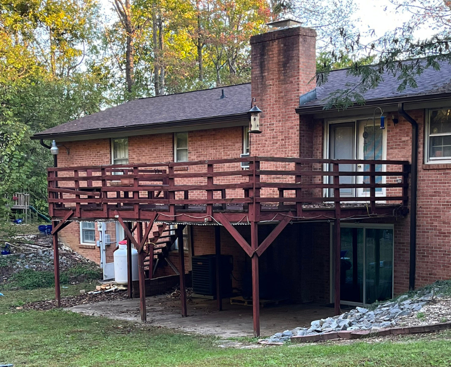 A brick house with a wooden deck in front of it.