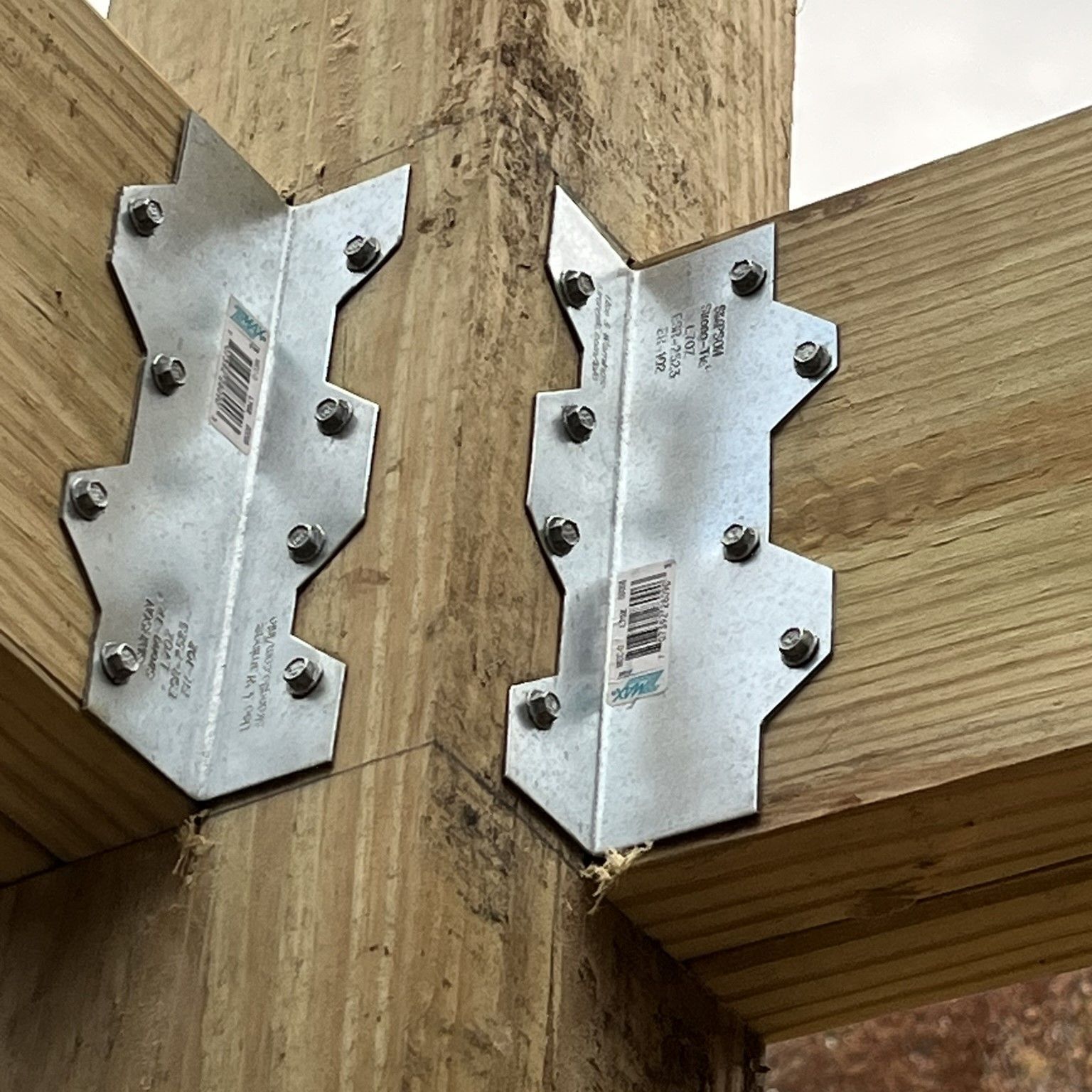 Two metal brackets are attached to a wooden beam.