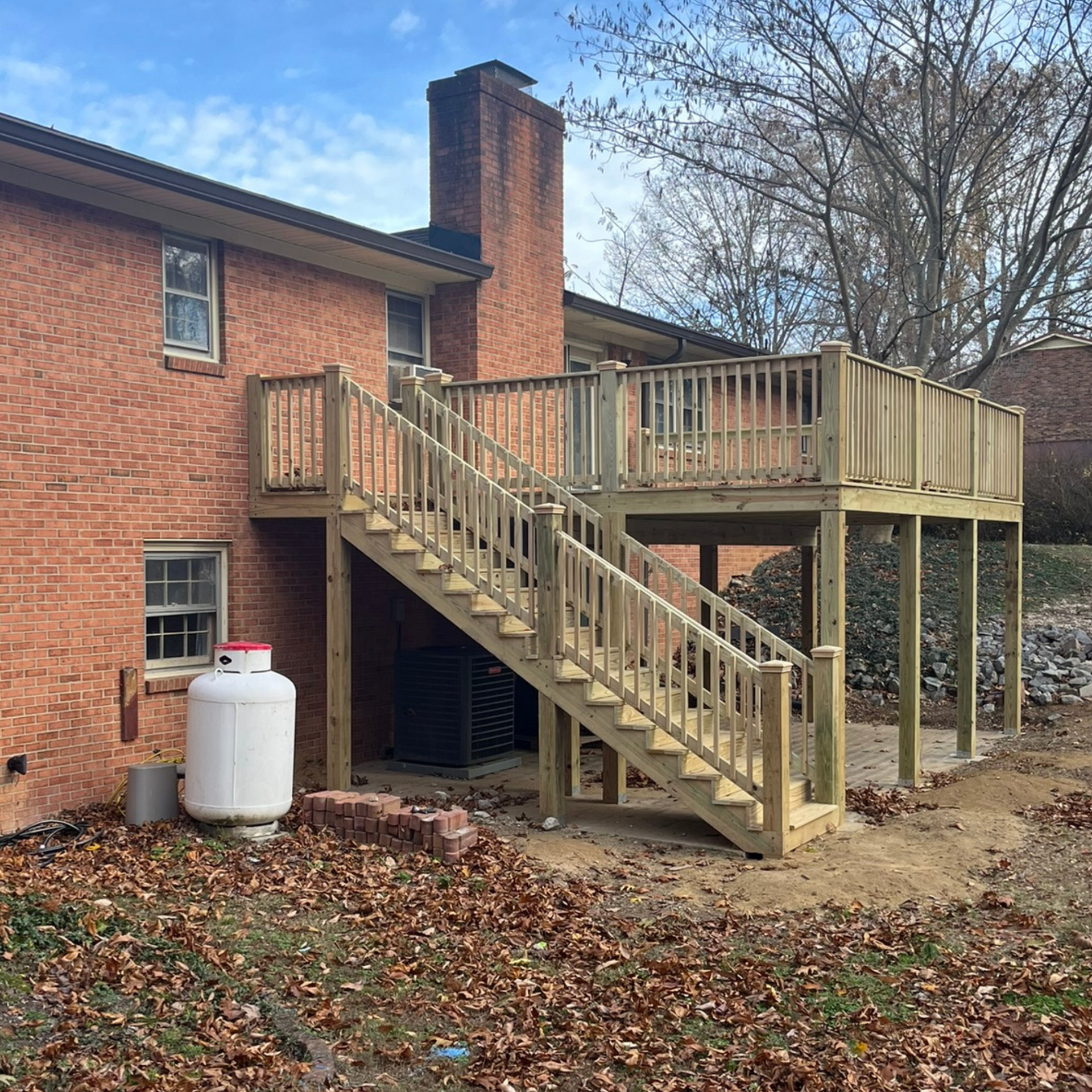 A brick house with a wooden deck and stairs leading up to it.