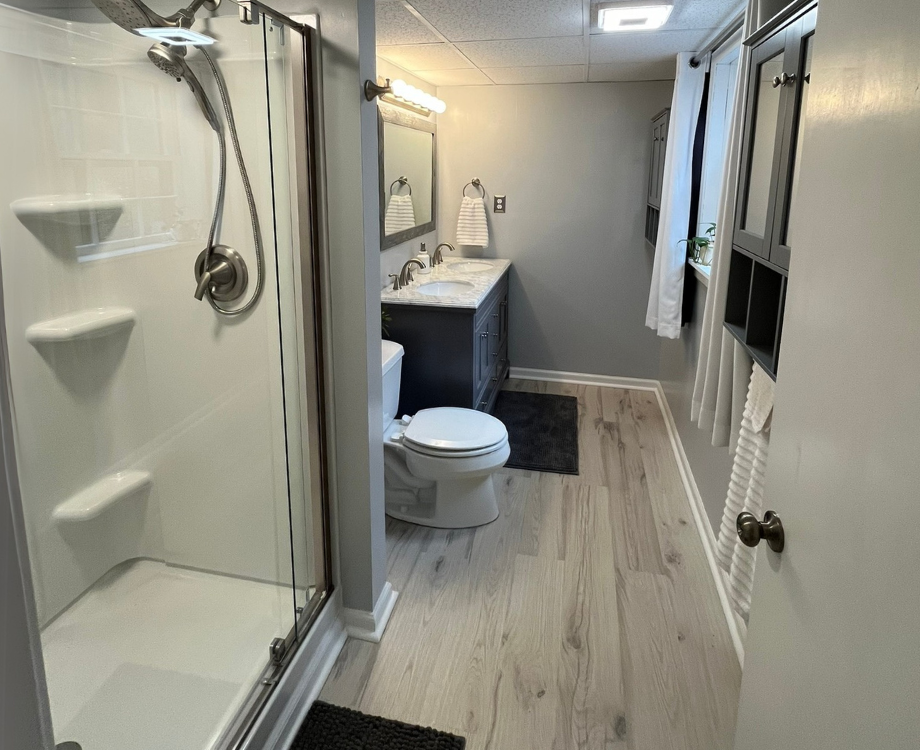 A bathroom with a toilet , sink and shower.
