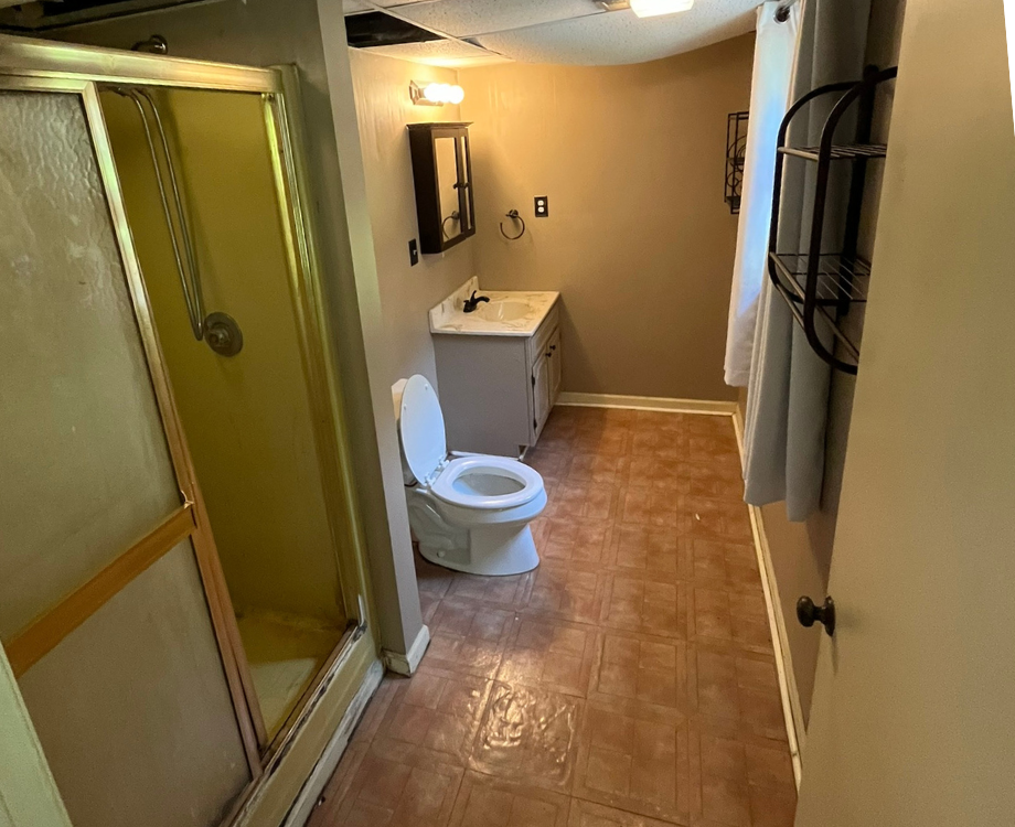 A bathroom with a toilet , sink and shower.