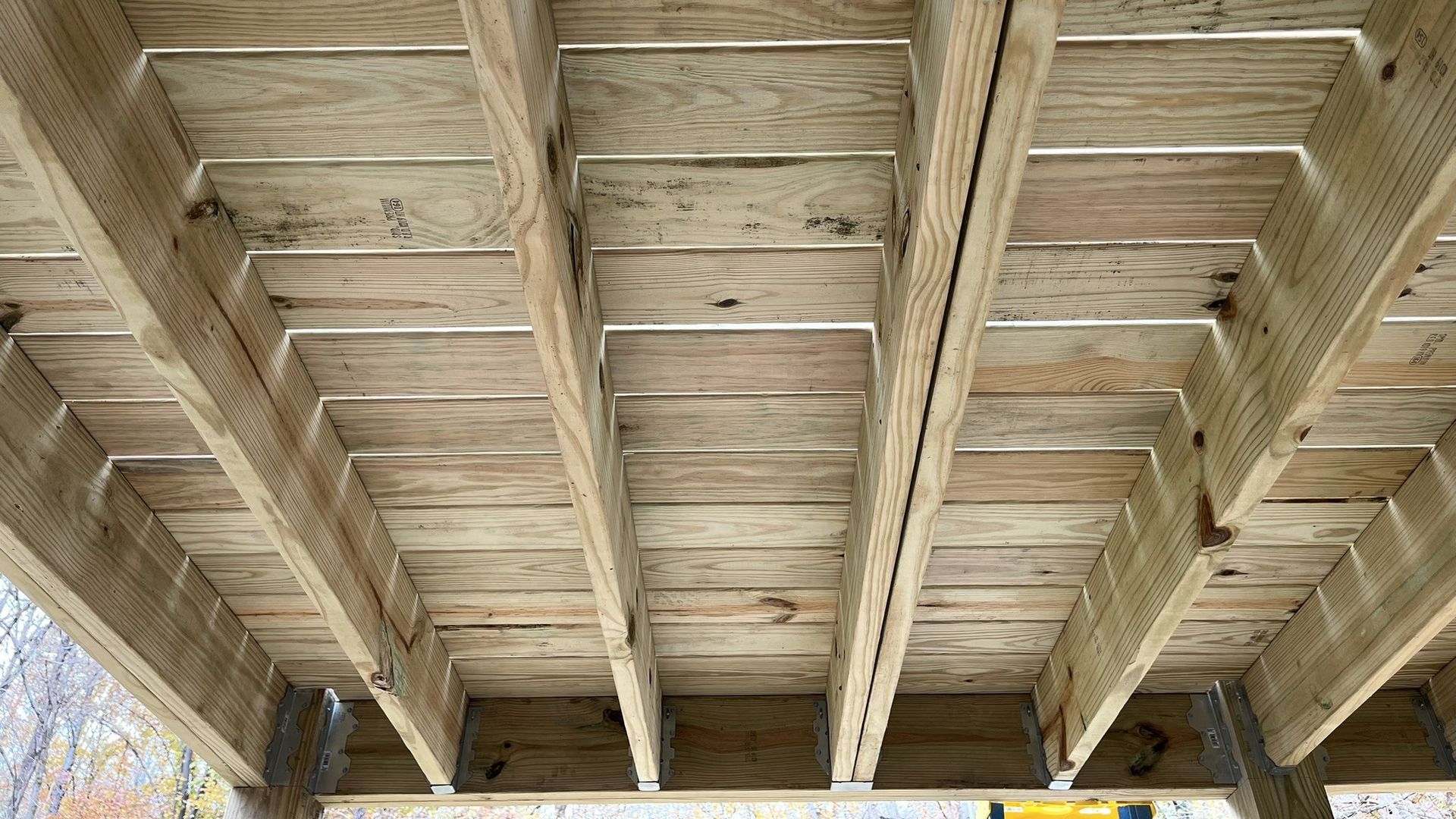 The ceiling of a wooden deck under construction.