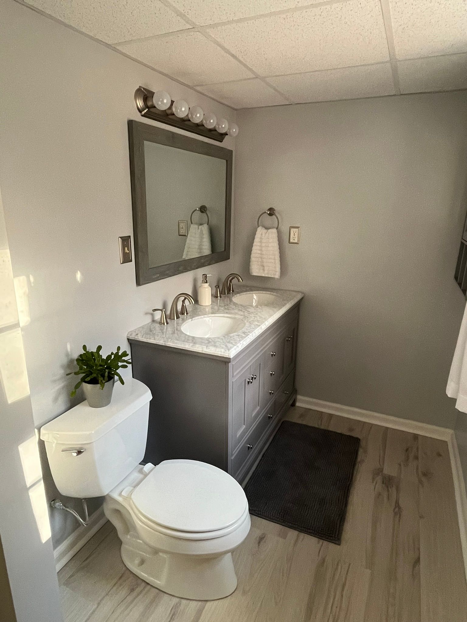 A bathroom with a toilet , sink and mirror.