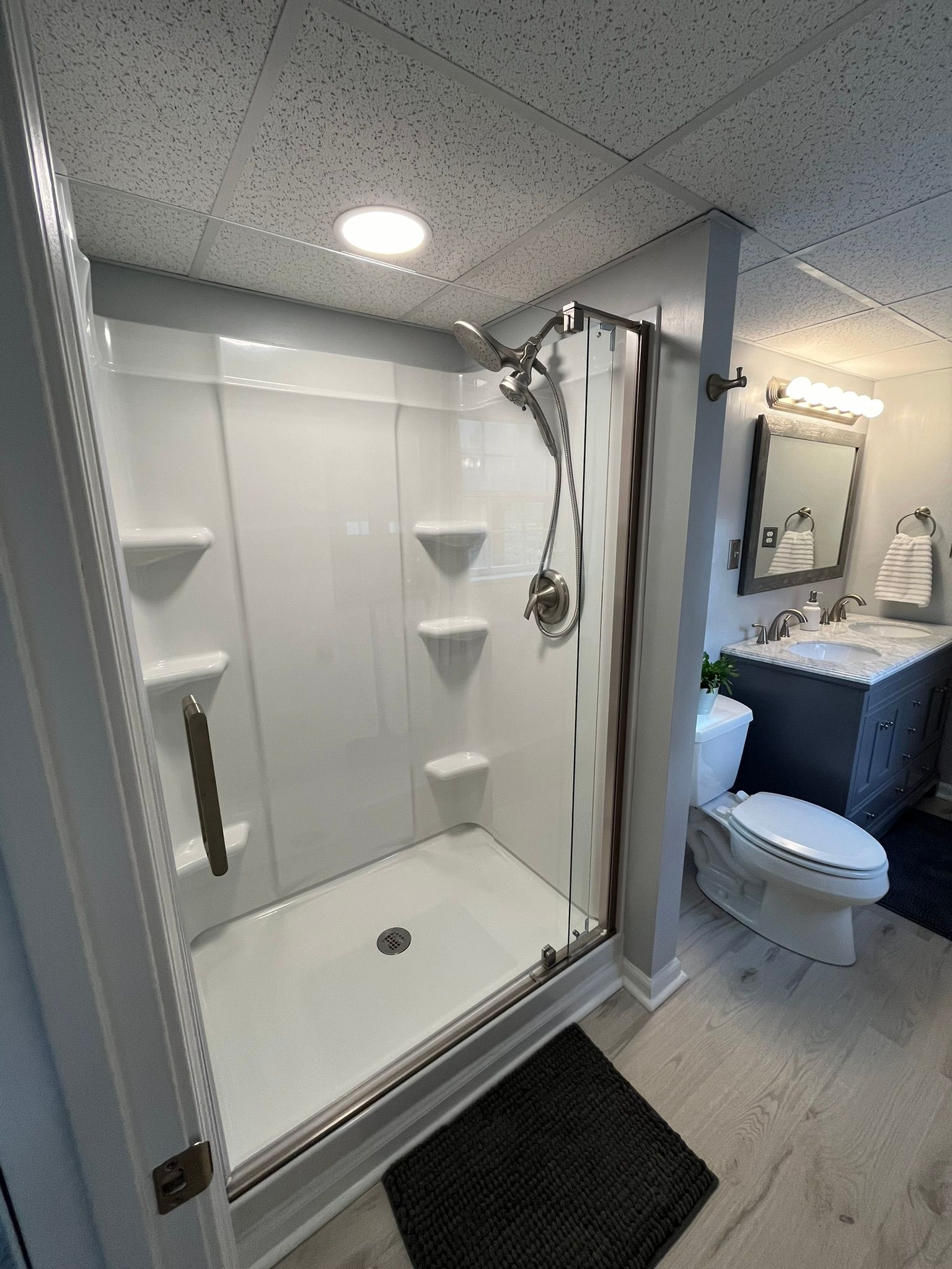 A bathroom with a shower , toilet , sink and mirror.