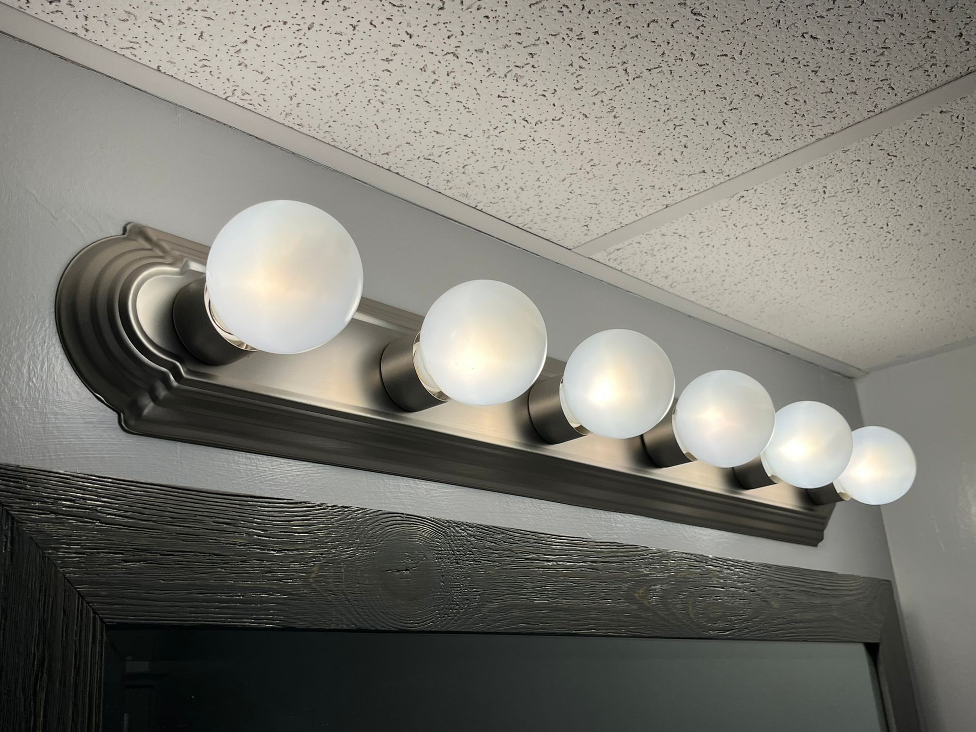 A bathroom vanity light with white bulbs hanging from the ceiling.