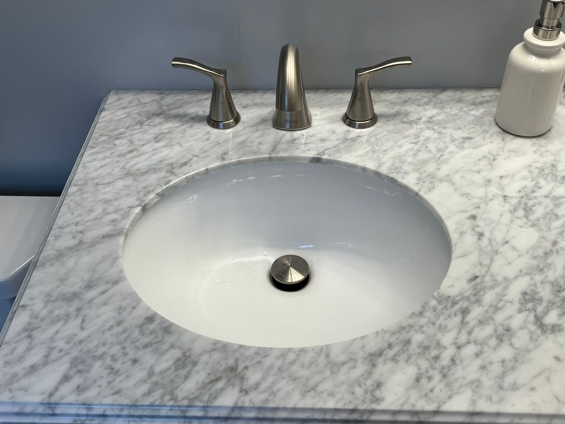 A bathroom sink with a soap dispenser next to it