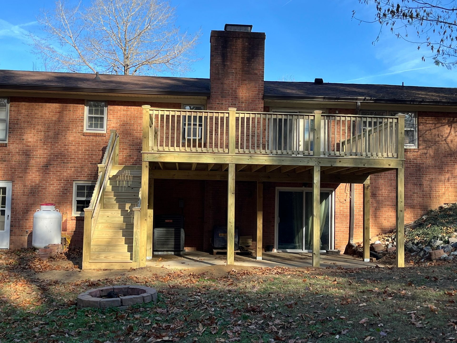 The back of a brick house with a wooden deck and stairs.