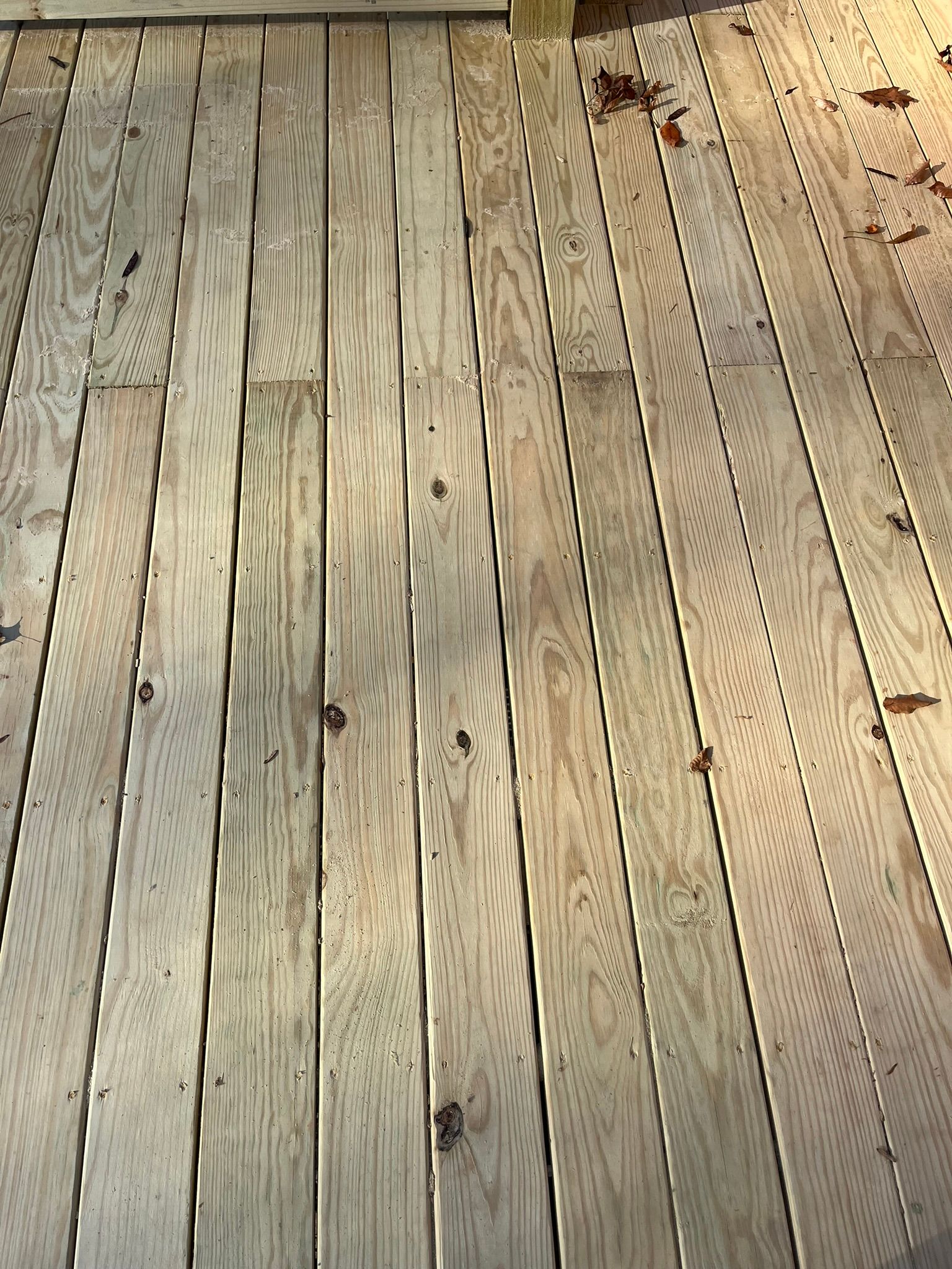A close up of a wooden deck with leaves on it.