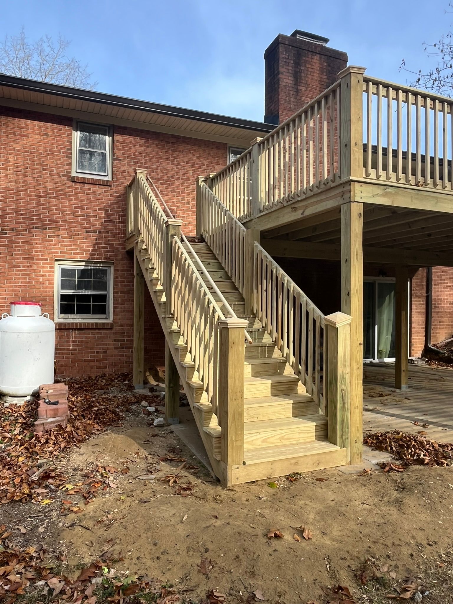 A wooden deck with stairs leading up to it in front of a brick house.