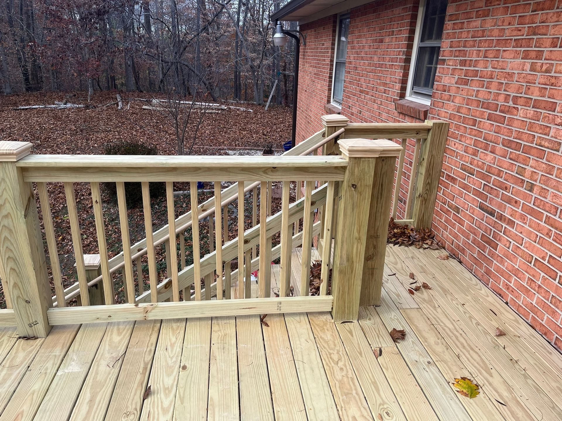 A wooden deck with stairs leading up to it in front of a brick house.