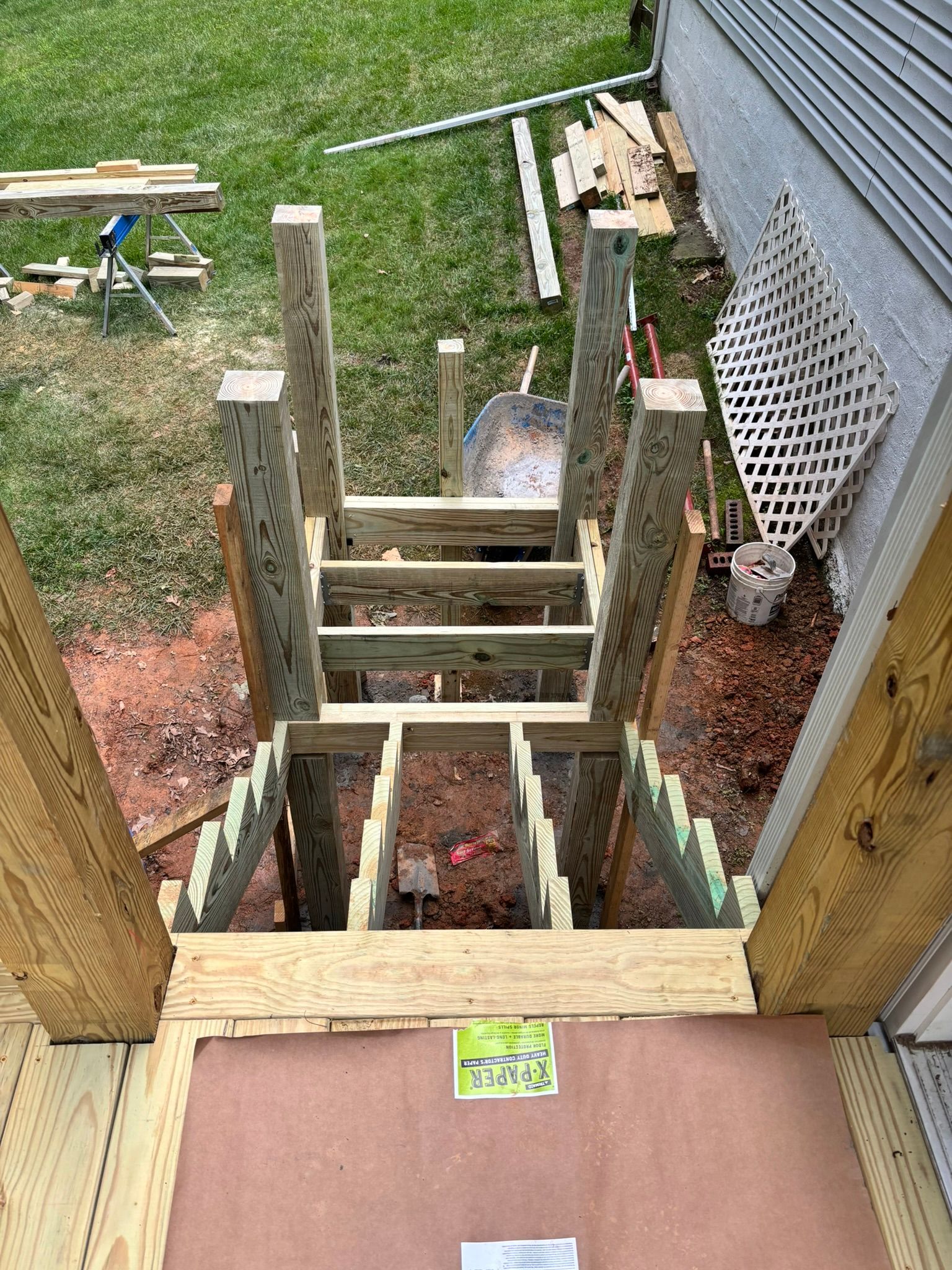 A wooden staircase is being built in the backyard of a house.