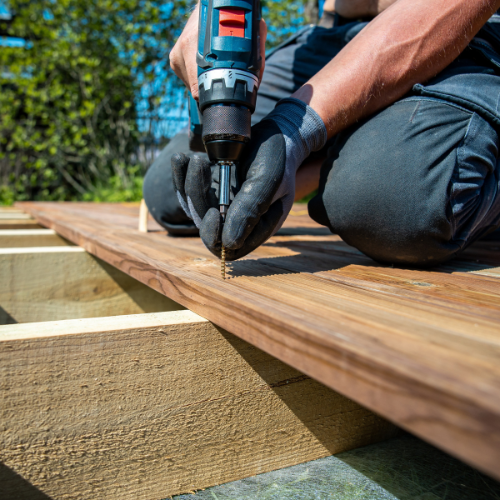 A man is using a drill to drill a screw into a piece of wood.