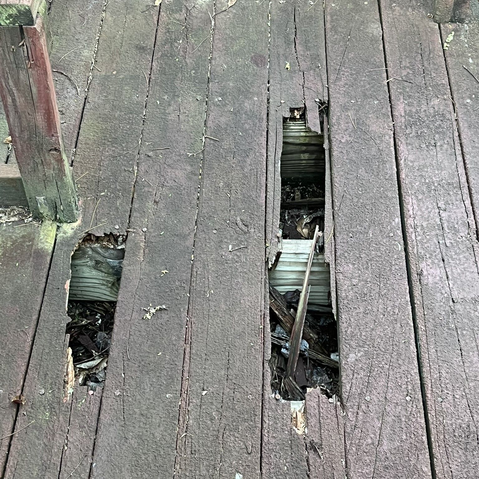 A close up of a wooden deck with a hole in it.
