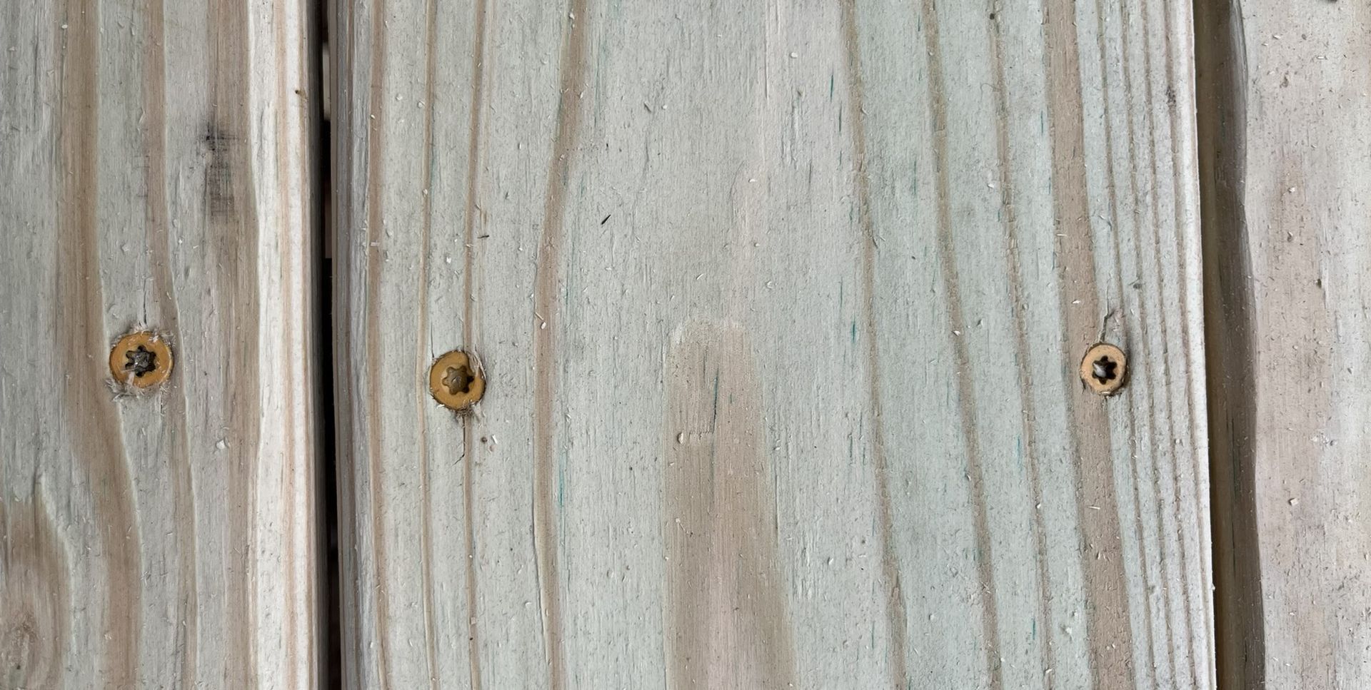 A close up of a piece of wood with screws in it.