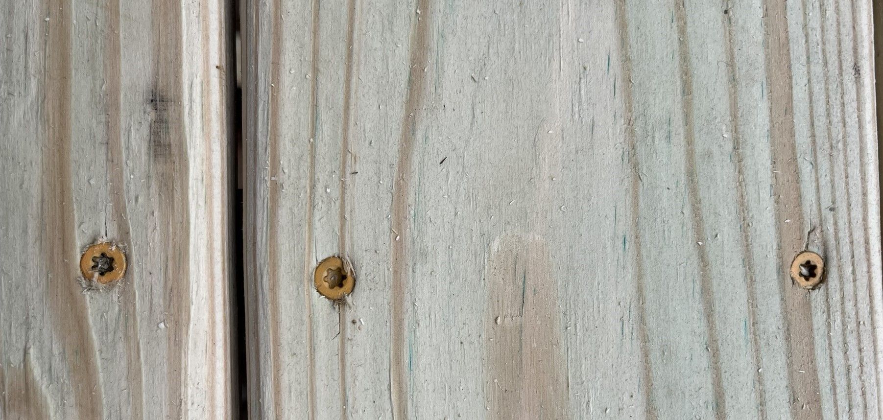 A close up of a piece of wood with screws in it.