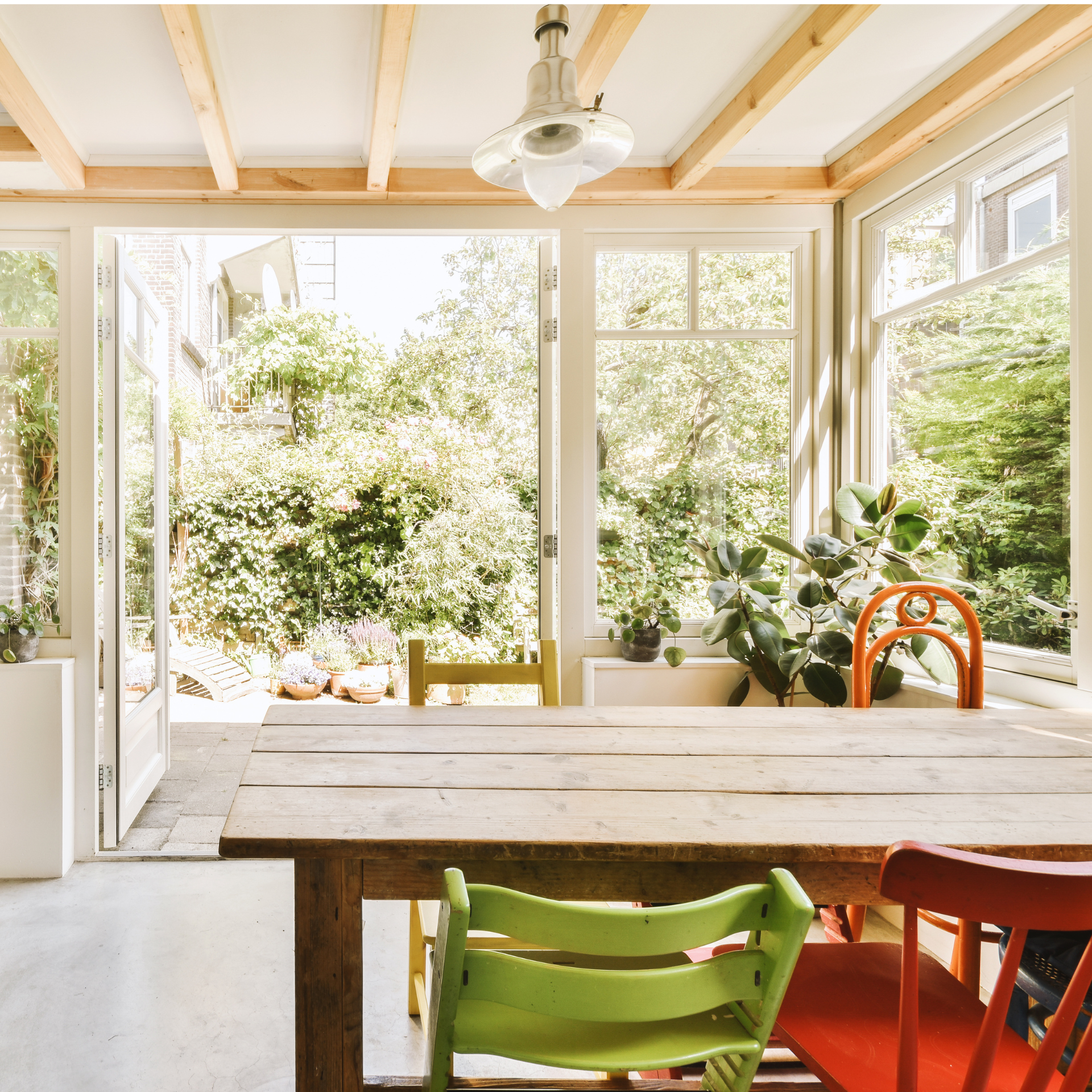 A wooden table and chairs in a room with lots of windows