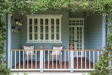 There is a porch with chairs and a table on it.
