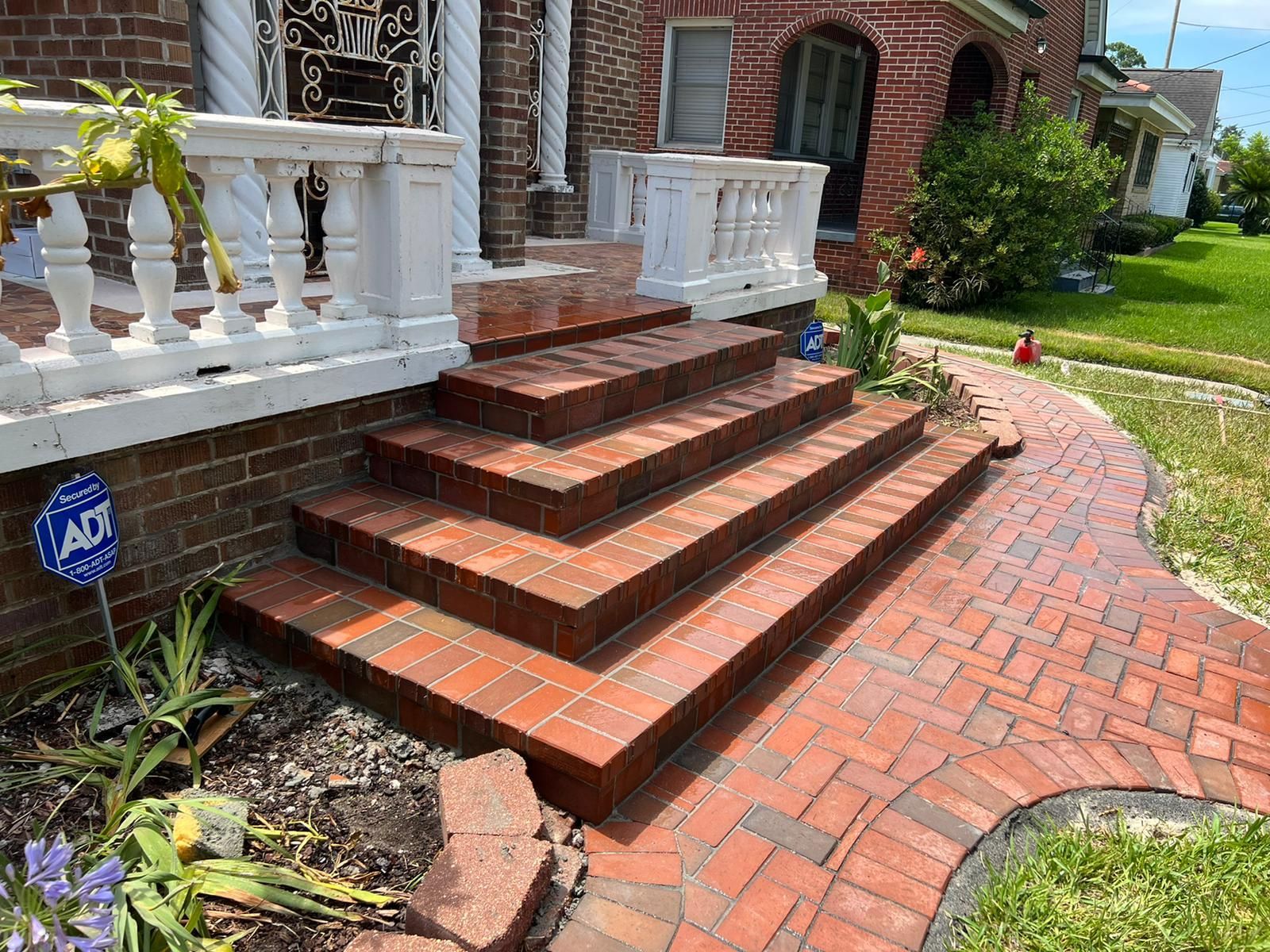 A brick walkway with stairs leading up to a brick house.