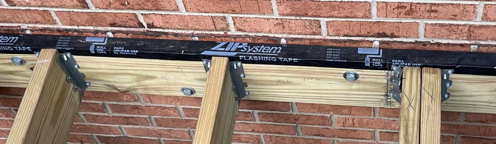 A wooden structure is being built on a brick wall.