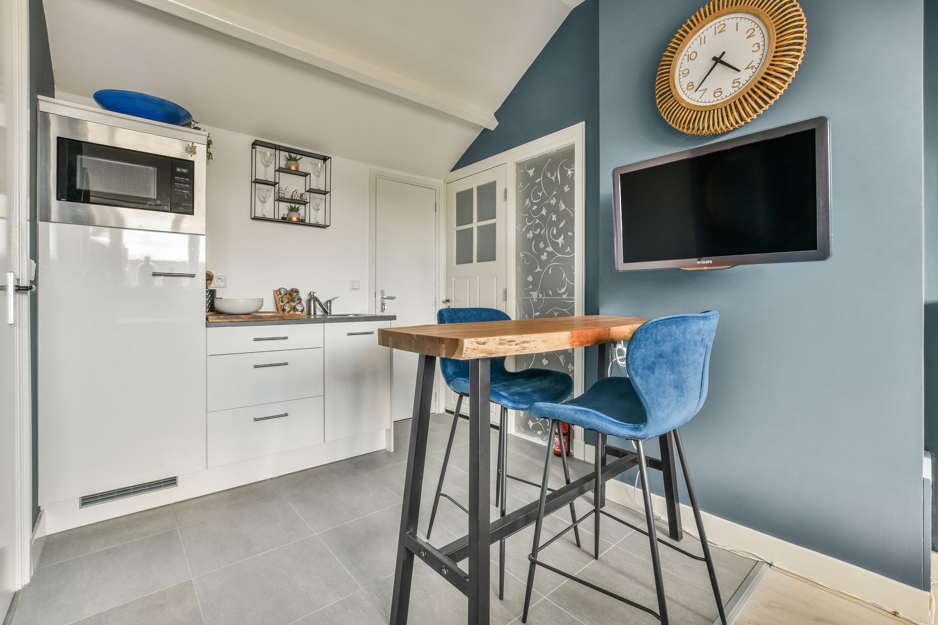 A kitchen with a table and chairs and a clock on the wall.