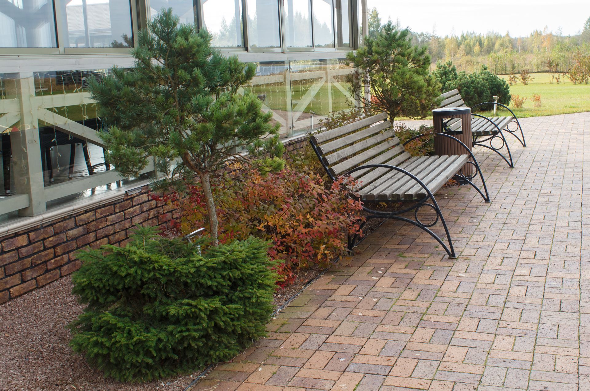 A row of wooden benches are sitting on a brick patio.