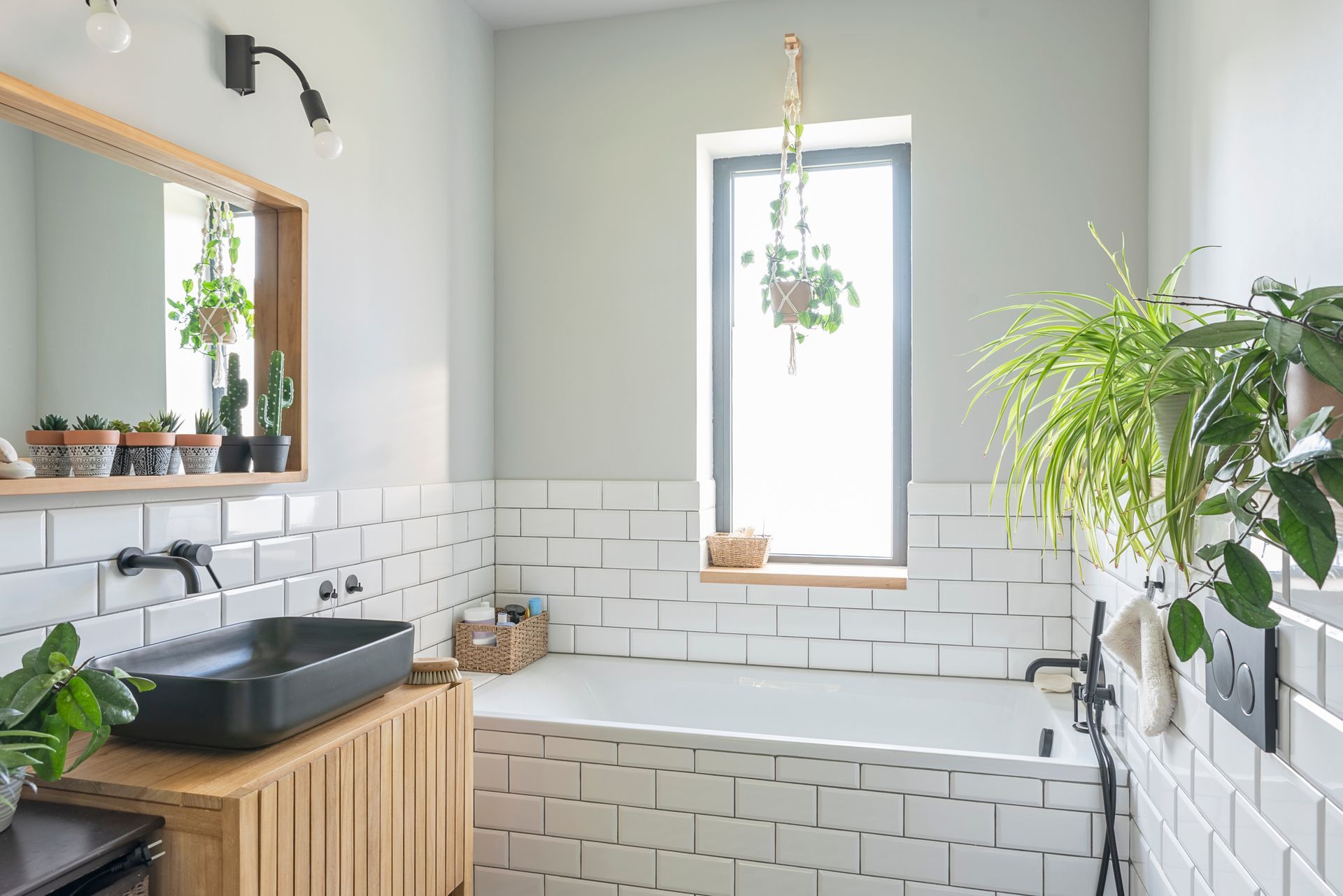A bathroom with white tiles , a sink , a tub and a window.