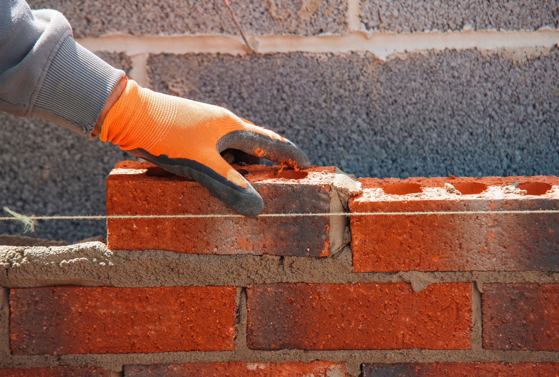 A person is laying bricks on a brick wall.