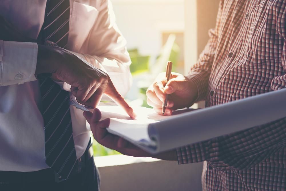 Two Men Are Standing Next to Each Other With Files — CWD Group in Springwood, QLD