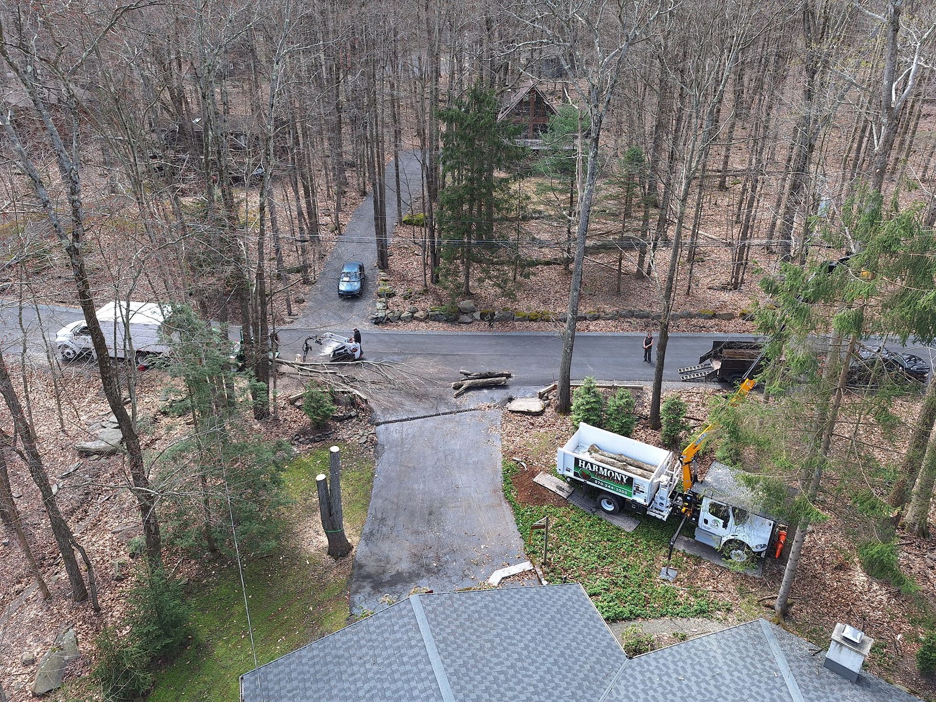 An aerial view of a house in the woods with a truck parked in front of it.