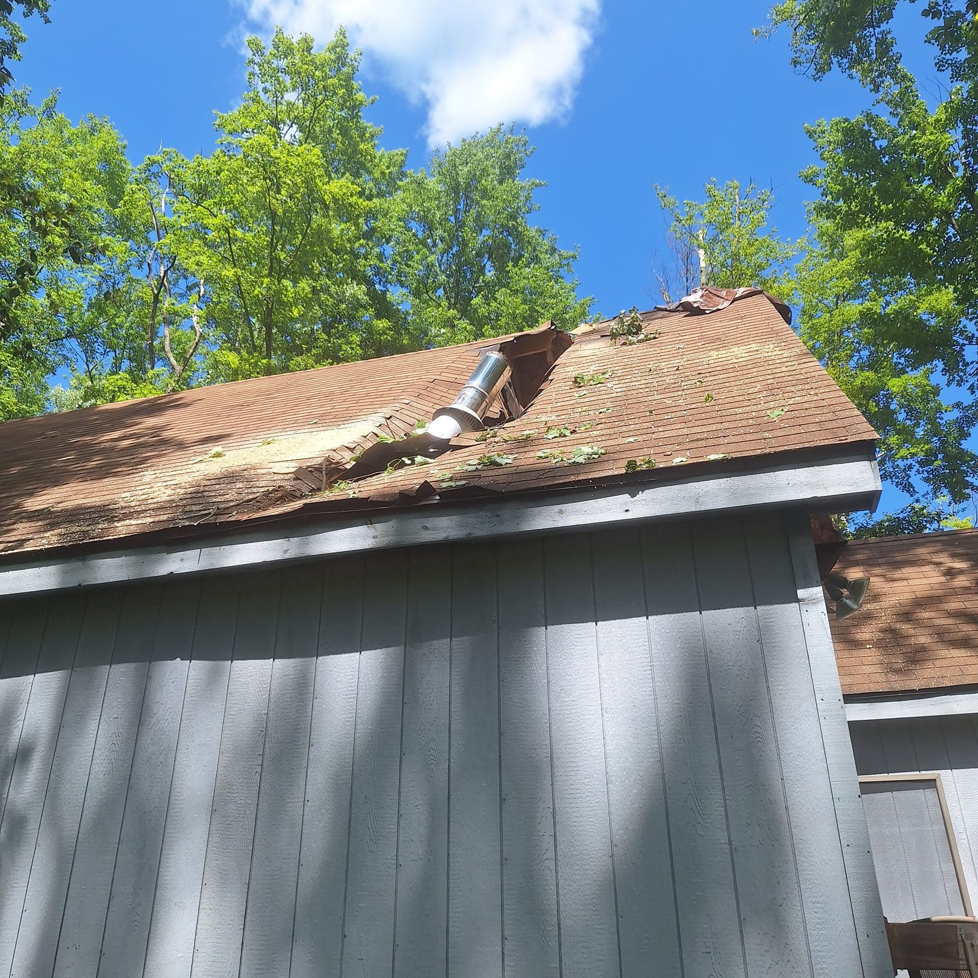 A roof with a hole in it and trees in the background