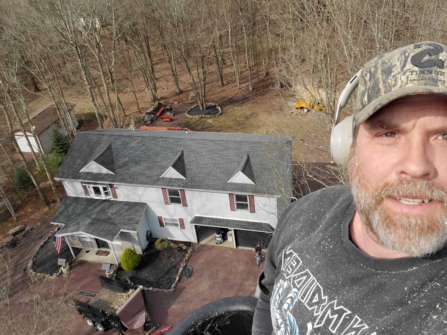 A man wearing headphones is standing in front of a house.