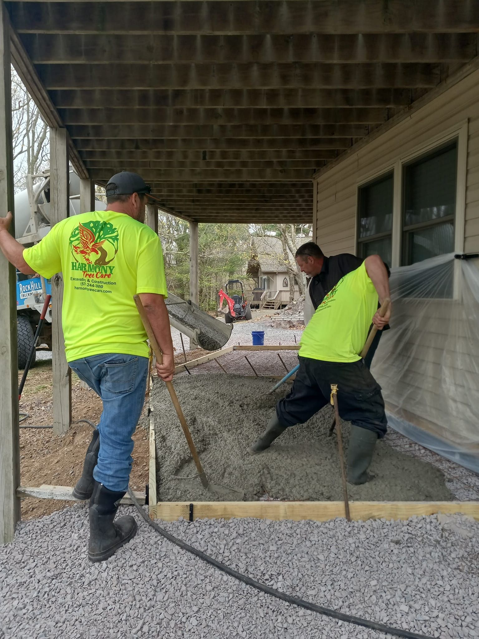 Two men are working on a concrete driveway under a porch.